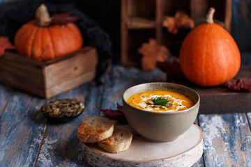 Vegetarian pumpkin cream soup. Autumnal pumpkin soup. Home made pumpkin cream soup decorated with cream, seeds, bread