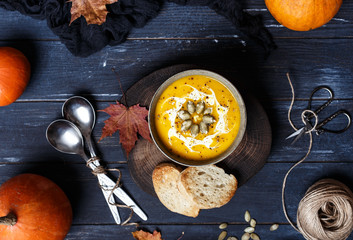 Vegetarian pumpkin cream soup. Autumnal pumpkin soup. Home made pumpkin cream soup decorated with cream, seeds, bread