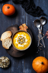 Vegetarian pumpkin cream soup. Autumnal pumpkin soup. Home made pumpkin cream soup decorated with cream, seeds, bread