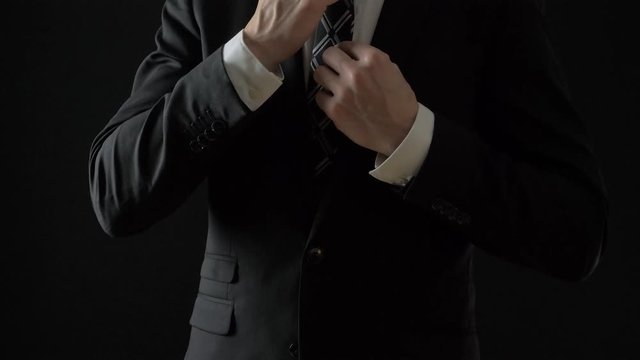 Elegant business man in white shirt correcting his tie and buttoning his suit jacket. close up