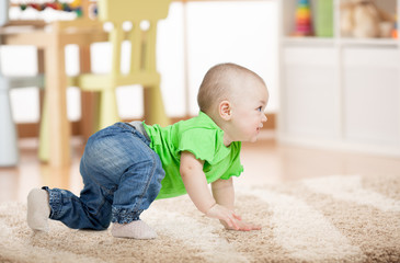 side view of baby crawling on soft carpet on floor in children room