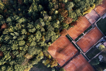 aerial drone view from above on tennis court between trees of a forest, autumn