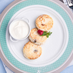 traditional russian or ukrainian breakfast syrniki - cottage cheese pancakes with honey and sour cream and raspberries
