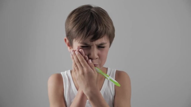 Lttle boy brushing his teeth in bathroom and stop becuse of a tooth pain. Dental problems