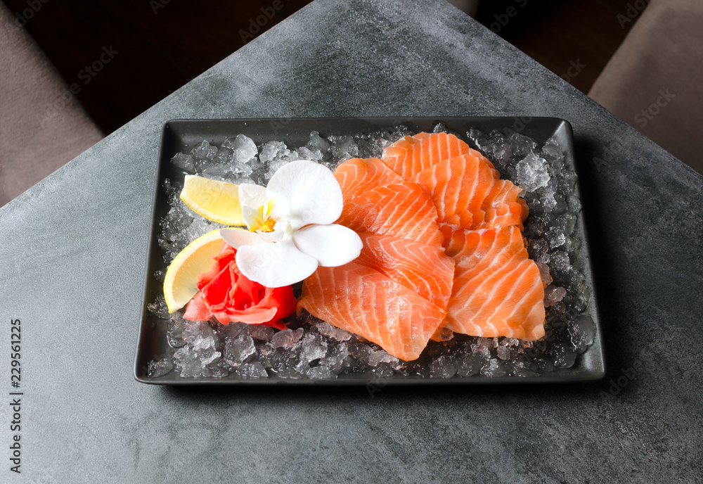 Wall mural Sashimi with trout and lemon on chipped ice with flower