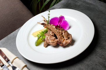 Rack of lamb with flowers on a white plate