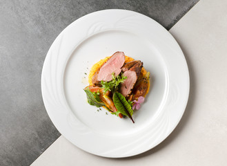 Duck fillet with figs and carrot puree on a white plate