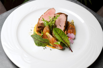 Duck fillet with figs and carrot puree on a white plate