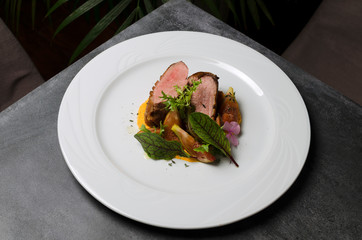 Duck fillet with figs and carrot puree on a white plate
