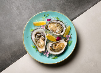 Oysters in ice with flowers and lemon on a blue plate