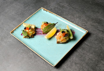 Salmon tar tar with lemon and toast on a blue plate