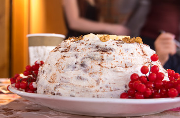 Cake covered with white cream and decorated with viburnum berries and pineapple