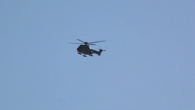 Black helicopter flying against the blue sky
