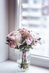 Delicate wedding bouquet stands in a circle on the window.