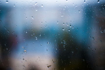 Drops Of Rain On Blue Glass Background. Street Bokeh Lights Out Of Focus. Autumn Abstract Backdrop