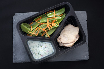 Potrawa obiadowa w diecie pudełkowej. Kurczak w ziołach z sosem jogurtowym z zieloną sałatką - obrazy, fototapety, plakaty