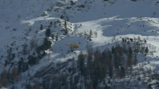 Yellow helicopter flying over mountain