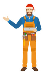 Worker in Santa hat holding digital tablet PC and showing something beside of him