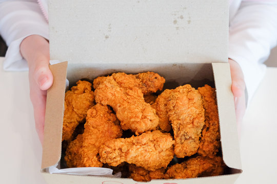 Hand Holding Delicious Crispy Fried Chicken Drumsticks & Wings For Snack Serve On White Boxes For Food Background Or Texture And Homemade Concept.