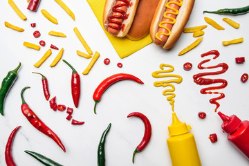 top view of delicious hot dogs, peppers and fries with mustard and ketchup on white surface - Powered by Adobe