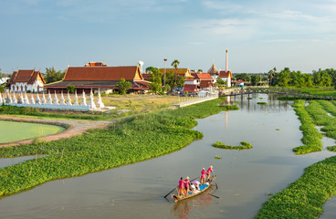 Tourists ride wooden boat in the canal, the view of nature and the temple.