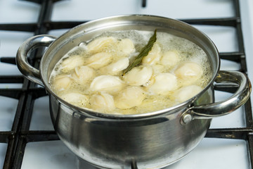 dumplings are cooked in a pot on a gas stove.