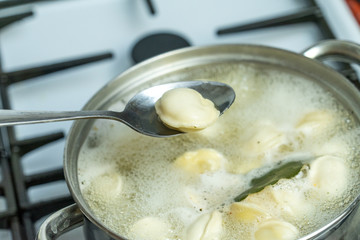 dumplings are cooked in a pot on a gas stove.