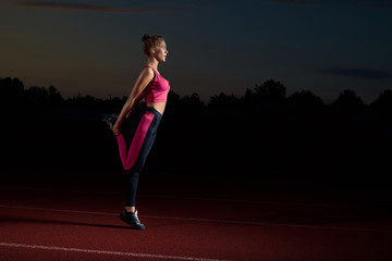 Sporty woman doing stretching for legs after running.