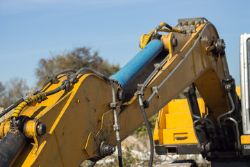 yellow boom of a large excavator with a hydraulic piston