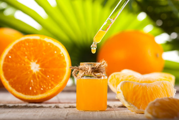 Orange Essential Oil on green leaves background