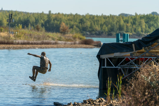 Participant Of An Obstacle Course Race Jumping From A Water Slide