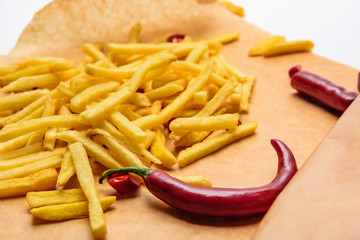 tasty french fries with spicy peppers on parchment paper on white