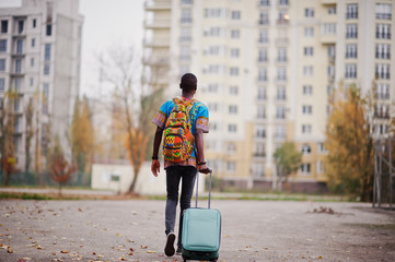 African man in africa traditional shirt on autumn park with backpack and suitcase. Emigrant...