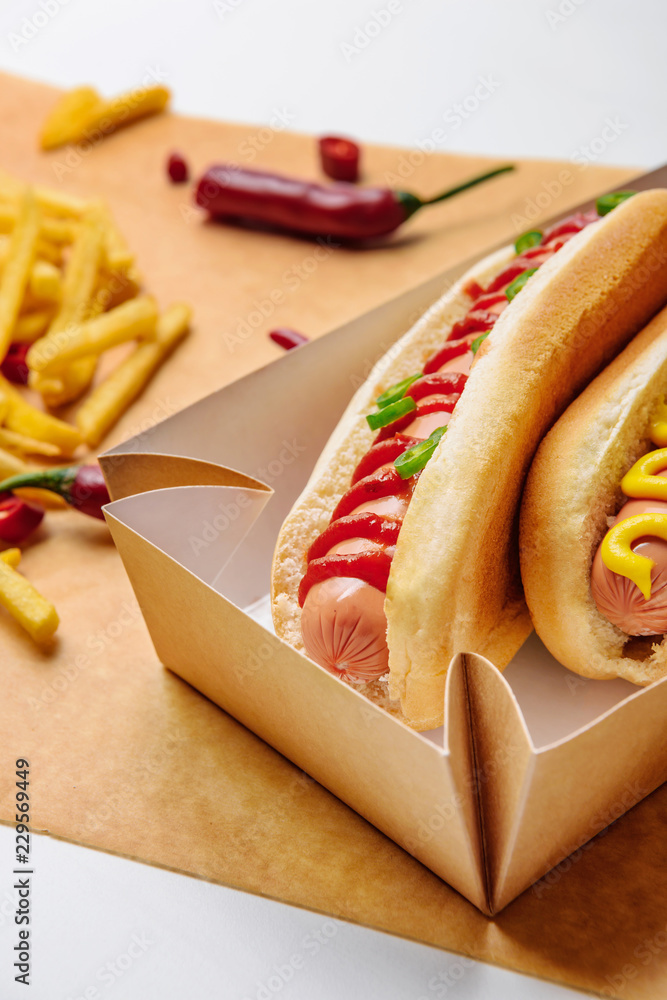 Canvas Prints close-up shot of hot dogs in cardboard tray with french fries on parchment paper