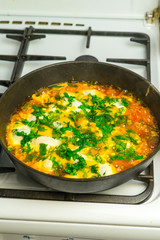 Cook shakshuka on a gas stove in a frying pan.