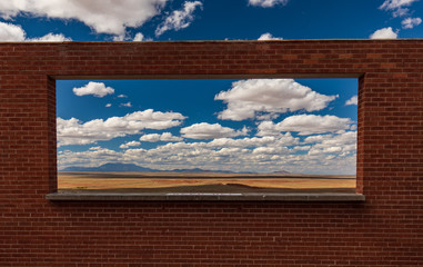 Looking through a brick wall window at a beautiful cloudy sky and valley