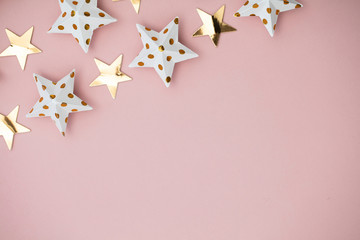 White and gold star decorations on a pastel pink. Seasonal festive background