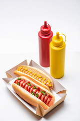 close-up shot of tasty hot dogs with mustard and ketchup on white
