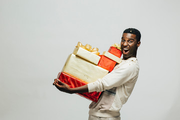 Portrait of an excited young man carrying many gifts , isolated on white studio background