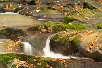 Obraz na płótnie Canvas Small mountain waterfall in autumn. A beautiful landscape full of peace. Looking at the mountain stream, you can relax and think.