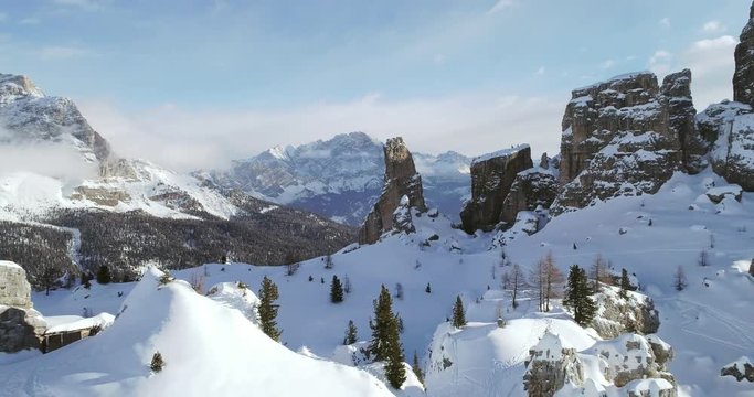 Backward aerial to snowy alpine valley with woods forest at Cinque Torri.Sunny sunset or sunrise,sunny day,cloudy sky.Winter Dolomites Italian Alps mountains outdoor nature establisher.4k drone flight