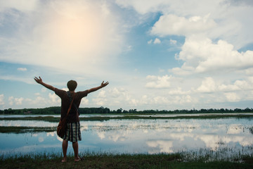 Fototapeta na wymiar Happy man with hands up on Sky and water Natural background.