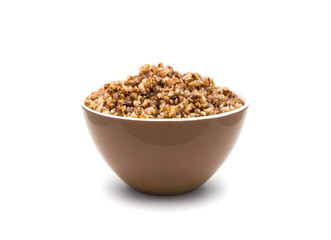 Dry buckwheat in brown ceramic bowl isolated on white