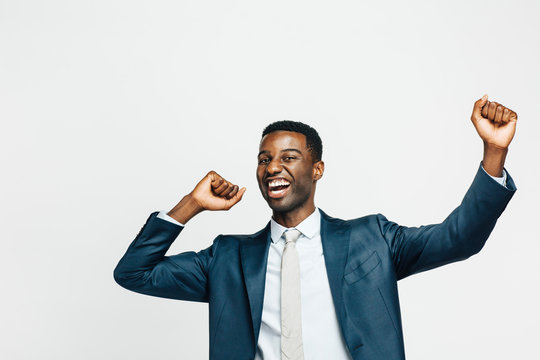 Did it!  Portrait of a happy young man in business suit with both hands up, isolated on white studio background