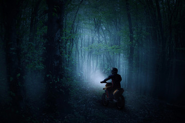A rider on a motorcycle in a haunted misty forest