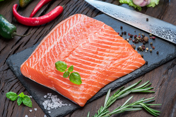 Fresh salmon fillet on black cutting board.