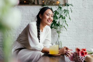 Smiling young woman with braided hair sitting at cafe