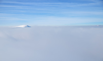 Fresh sparkling snow cover on mountain tops. Blue sky at the background.