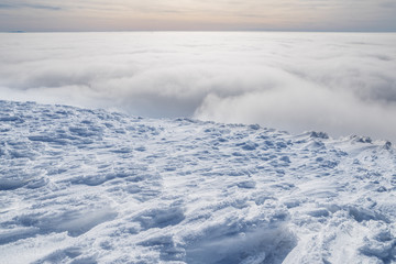 Fresh sparkling snow cover on mountain tops. Cloudy sky at the background.