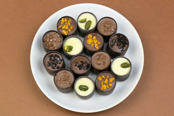 Chocolate candy on a white plate. Sweet beautiful candy lying on a plate on a bright color background.